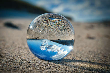 glass sphere on the beach of the baltic sea. detailed close up of the sphere with reflection of the...