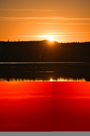 Sunset with reflection on a Swedish lake in Smalland. Romantic evening mood. Landscape shot from Scandinavia in natureの写真素材