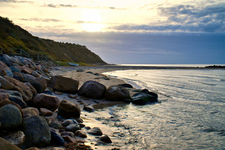 Sunset on the Danish coast. Beach, waves. Hill with trees in background. Landscape photo from seaの写真素材