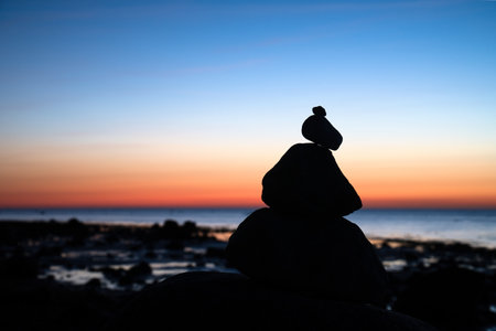 Stone pyramid on the Baltic Sea with a view of the sea at sunset and blue hour. Stones as silhouette. Spiritual view. Landscape shot from Poel islandの写真素材