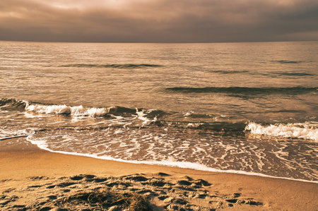 On the coast of the Baltic Sea at sunset. Waves roll onto the sandy beach. Nature photo by the seaの写真素材