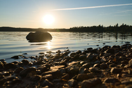 Lake in Sweden, smalland at sunset with rock in foreground of water with forest in background. Landscape shot from nature in the northの写真素材