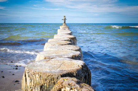 Groynes jut out into the Baltic Sea. Wooden trunks to protect the coast. Landscape from the seaの写真素材
