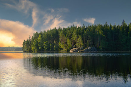 Lake in Sweden at sunrise with romantic light, blue water and trees on the shore. Scandinavian nature in the northの写真素材