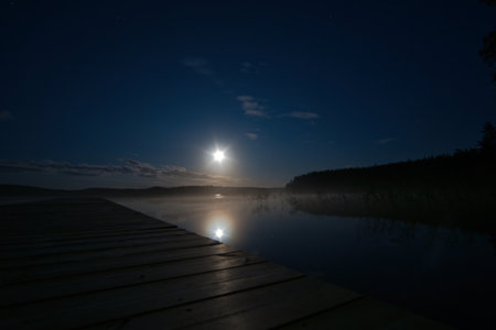 Moonlight over a lake in Sweden into which a wooden stay reaches. Scandinavian natureの写真素材