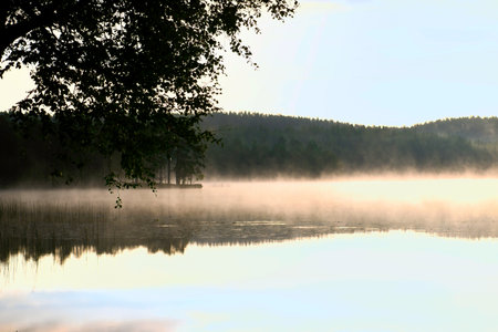 Sunrise with fog forming over a lake in Sweden, at dawn. Romantic silence, in the Scandinavian natureの写真素材