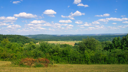 Vast landscape with green forests, rolling hills and a blue sky with white clouds. Idyllic nature, peace and freedom in a summery setting.の写真素材