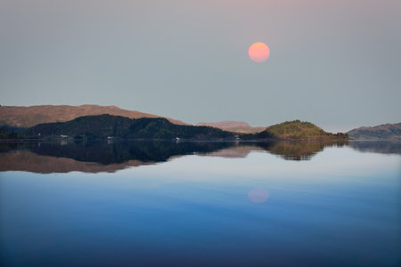 Fjord with view of mountains and fjord landscape in Norway. Red moon, calm mirror-smooth water. Scandinavian landscape shotの写真素材