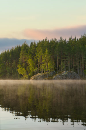 Sunrise with fog forming over a lake in Sweden, at dawn. Romantic silence, in the Scandinavian natureの写真素材