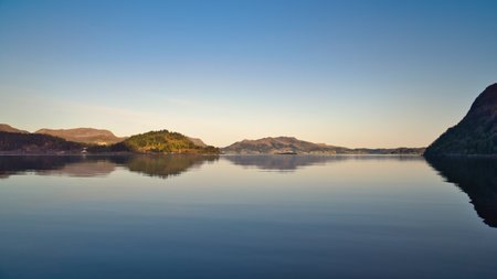 Fjord with view of mountains and fjord landscape in Norway. Blue sky, calm mirror-smooth water. Scandinavian landscape shotの写真素材