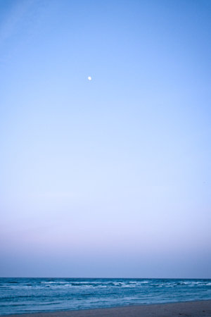 Moon in the sky in front of the beach. Landscape shot of the coastの写真素材