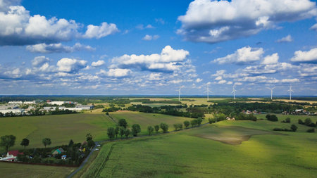 A vast agricultural landscape with wind turbines under a blue sky. A symbol of sustainable energy production in harmony with nature and agriculture.の写真素材