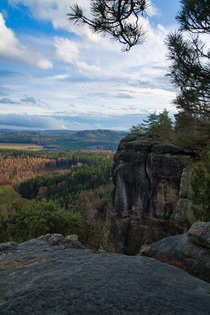 Majestic rock formation rises above a forested valley under a blue sky, perfect backdrop for adventure, nature and wanderlustの写真素材
