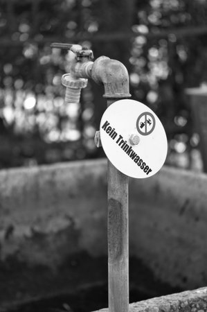 Old outdoor faucet with warning sign "Not for drinking water", rusty, unused, symbol of hygiene, safety and environmental awarenessの写真素材