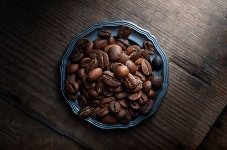 coffee beans on a plate on a wooden background.の写真素材