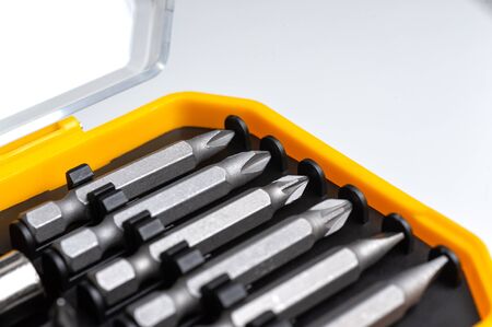 interchangeable screwdriver bits in a plastic box close-up macro isolated on a white background.