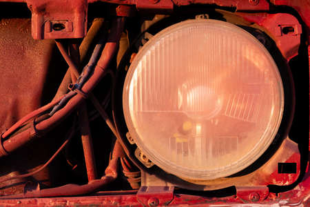 part of the face and headlight of a disassembled red car. High quality photoの写真素材