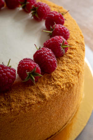 Russian honey cake decorated with raspberries on a wooden background. High quality photo