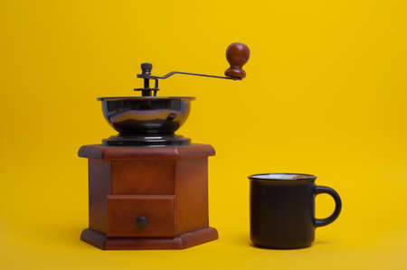 coffee cup and manual coffee grinder on yellow background. High quality photoの写真素材