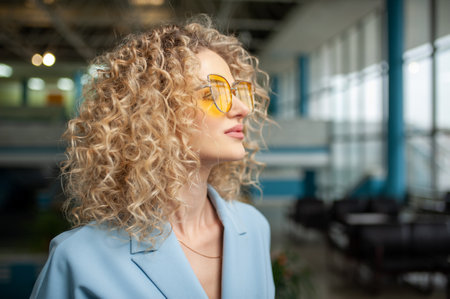 beautiful young girl in yellow glasses looks out the window at the airportの写真素材