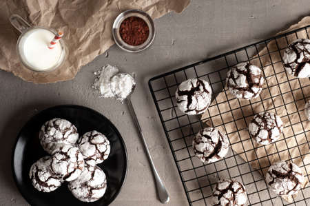 Deliciouse Homemade Chocolate crinkle cookies with powdered sugar icing grate for cooling on dark...