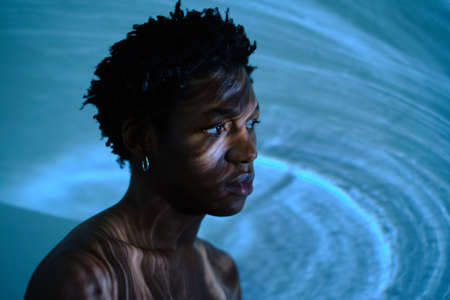 portrait of a young african american man on a blue background with shadows