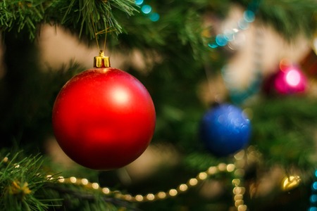 Red christmas decorative ball on the xmas tree on glitter bokeh background with twinkle lights. Merry christmas card. Happy New Year.の写真素材