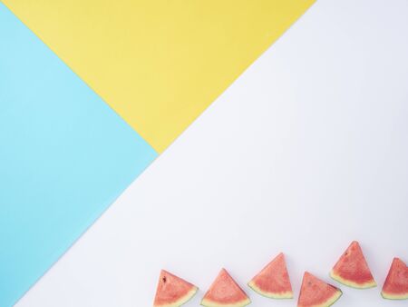 Colorful background with yellow, blue and watermelon slice on white. Space for text, flat lay.の写真素材