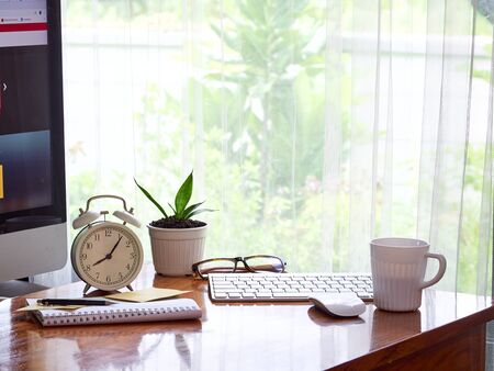 Image of working desk computer mouse, notebook, cup of coffee with small plant in white pot on brown wooden table.の写真素材