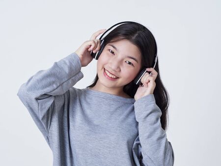Teen girl with headphones listening to music isolated on white background. Studio shot.の写真素材