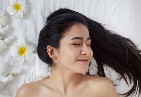 Beautiful woman and spa accessories, frangipani flowers, herbal compress ball, virgin coconut oil,...