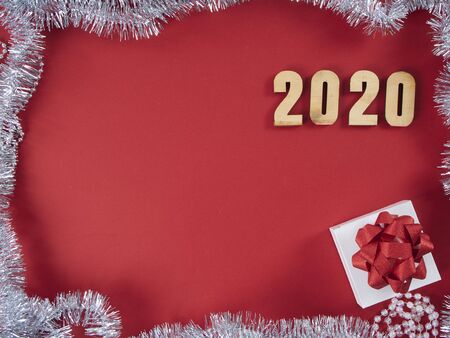 Christmas and New Year greeting card with composition festive decorations. Gift boxes and symbol from number 2020 on red background.の写真素材