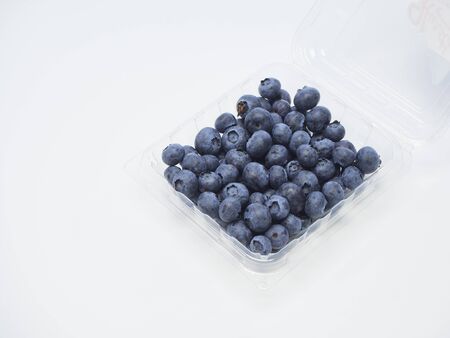 Freshly blueberry in a plastic box packed on a white background. space for textの写真素材