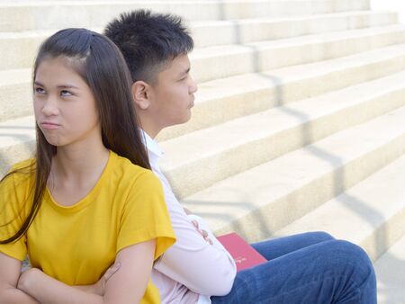 Young teens men and women conflicting sitting on stairs in school