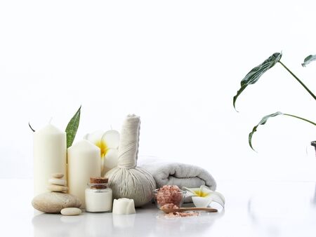 Spa massage concept, herbal compress ball, cream, flower soap, scented candle and Himalayan pink salt, isolated on whiteの写真素材