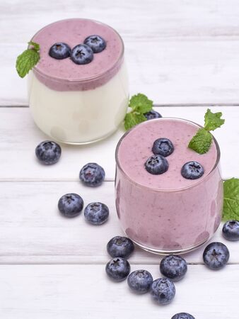 Two glasses of blueberry yogurt on a white wooden table. Healthy breakfast, diet food. space for text, close upの写真素材