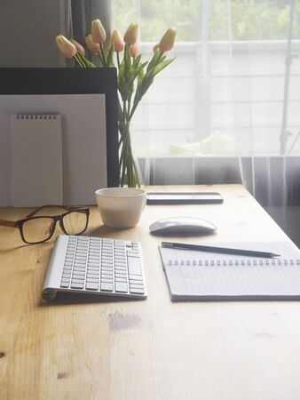 Working desk with computer, keyboard, smartphone, eyeglasses and cup of coffee at home.の写真素材