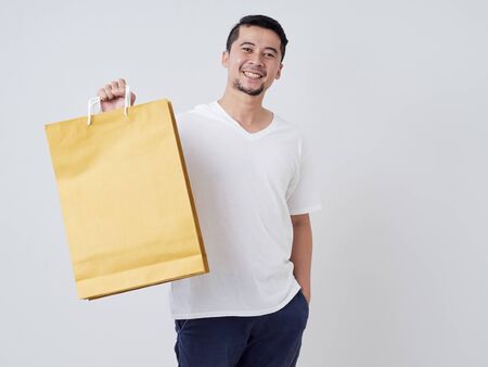 Portrait of young man with shopping bags while standing on white background.の写真素材