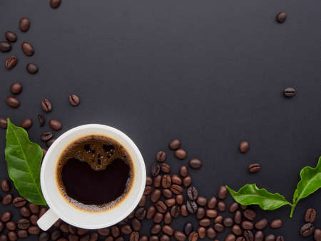 Coffee cup with roasted coffee beans, coffee leaves on black background. Top view , space for textの写真素材