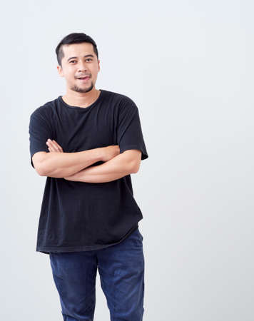 Smiling handsome man in T-shirt while standing crossed arms.