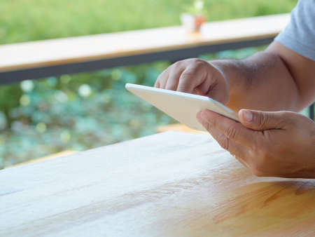 Close-up of a man using tablet in outdoor park.