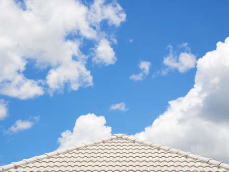 Roof of house under bright sky with white fluffy cloudsの写真素材