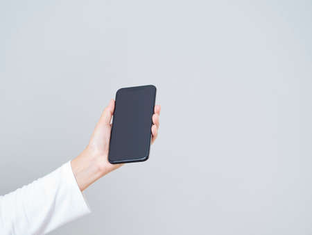 close-up of woman hand holding smartphone with blank screen, mock-up on white backgroundの写真素材