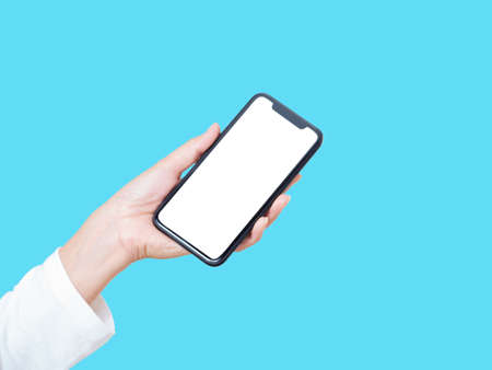close-up of woman hand holding smartphone with blank screen, mock-up on blue background