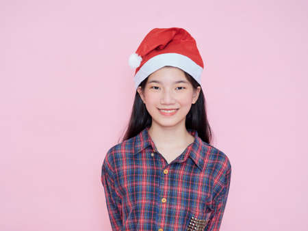 Studio portrait of young girl wearing santa hat on pink background. Christmas concept.の写真素材