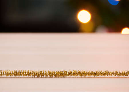 Christmas decorations, gold tinsel on wooden table against bokeh lights backgroundの写真素材