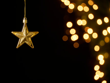 Golden Christmas star hanging against blurred festive lights, closeup, space for text