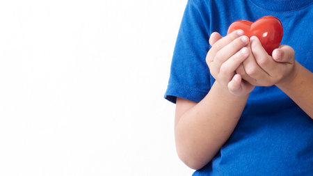 Child hand holding red heart on light background. Mother's day conceptの写真素材