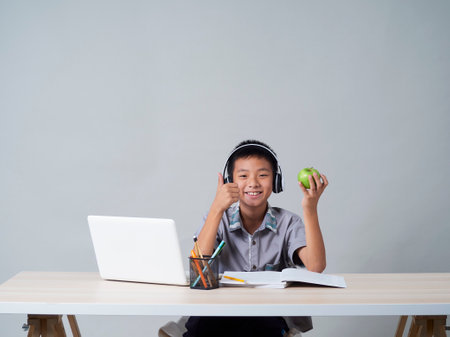 Little boy in headphones studying online using laptop. Social distance during quarantineの写真素材