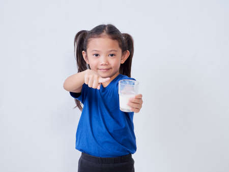 Portrait of little girl with glass of milk on light background. Space for textの写真素材